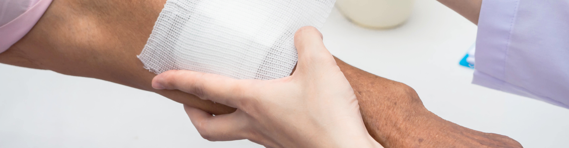 person dressing a wound of elderly person