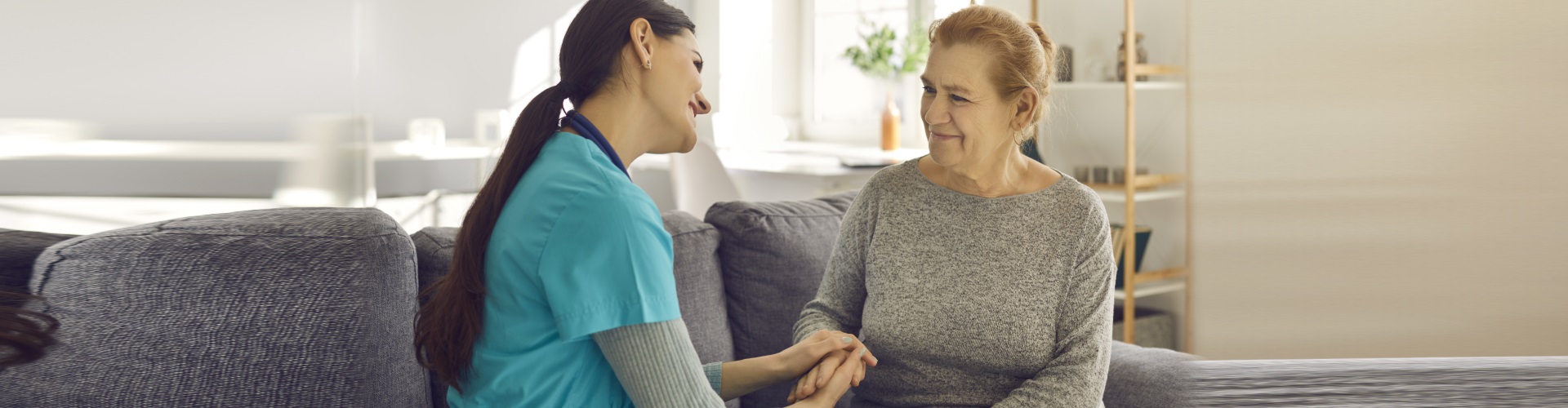 nurse holding womans hand on a couch